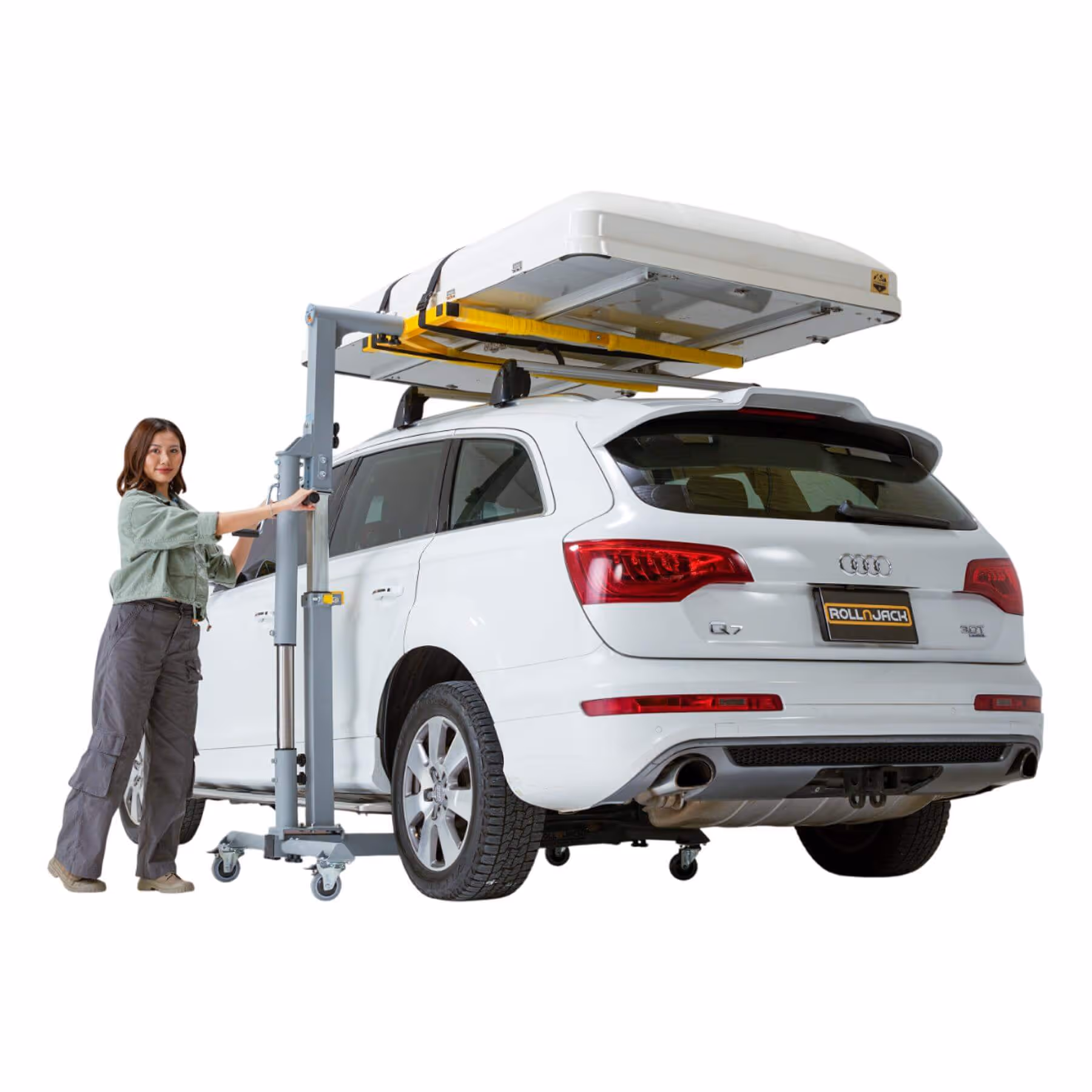 Woman operating a portable lift raising a white Audi Q7 SUV with a rooftop cargo box.