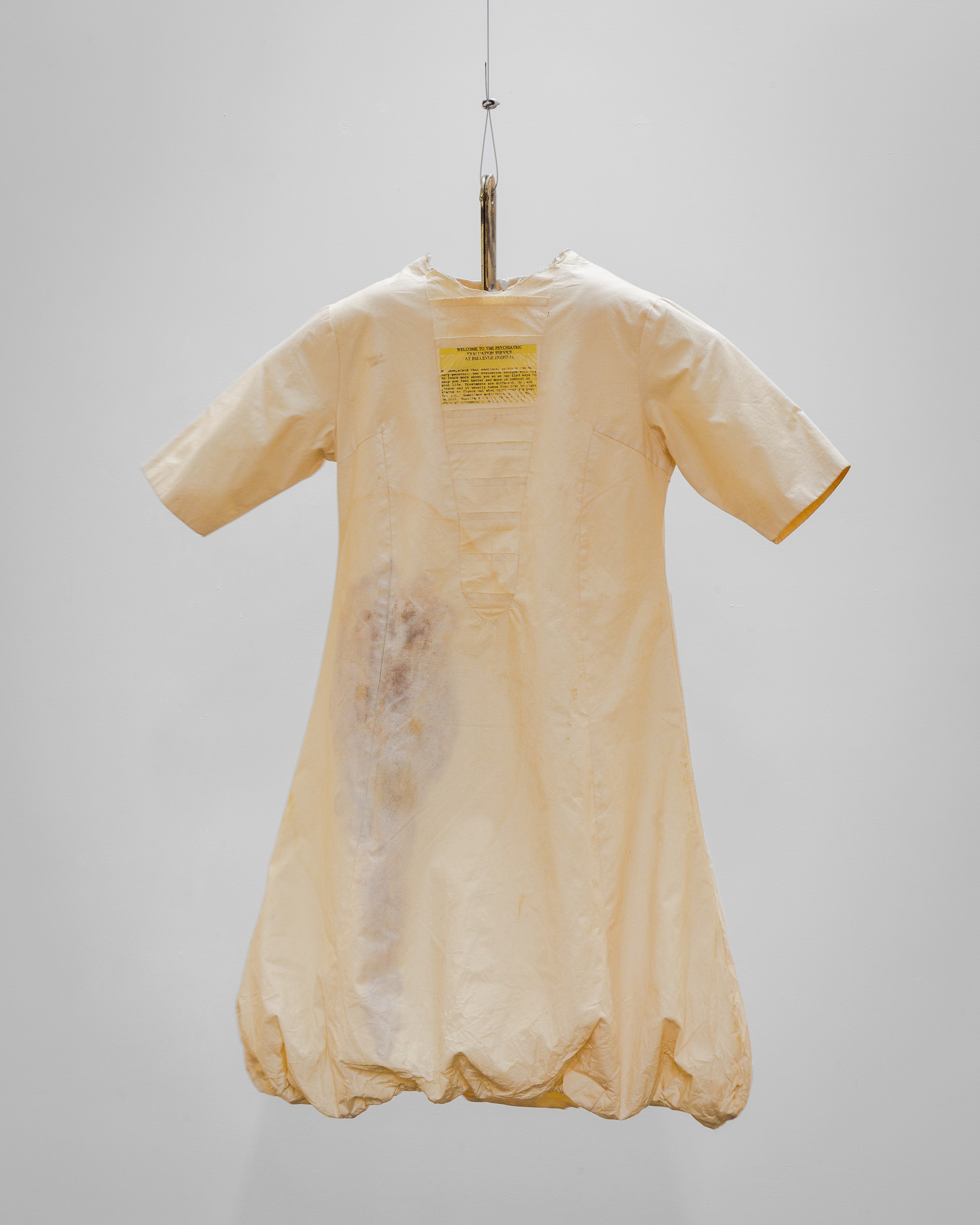 Patricia Ayres, Bellevue Hospital Dress , 2001- 2025, Muslin, text, paint, Ford Crown Victoria Police Interceptor restraint bracket, 40 x 30 x 8 in