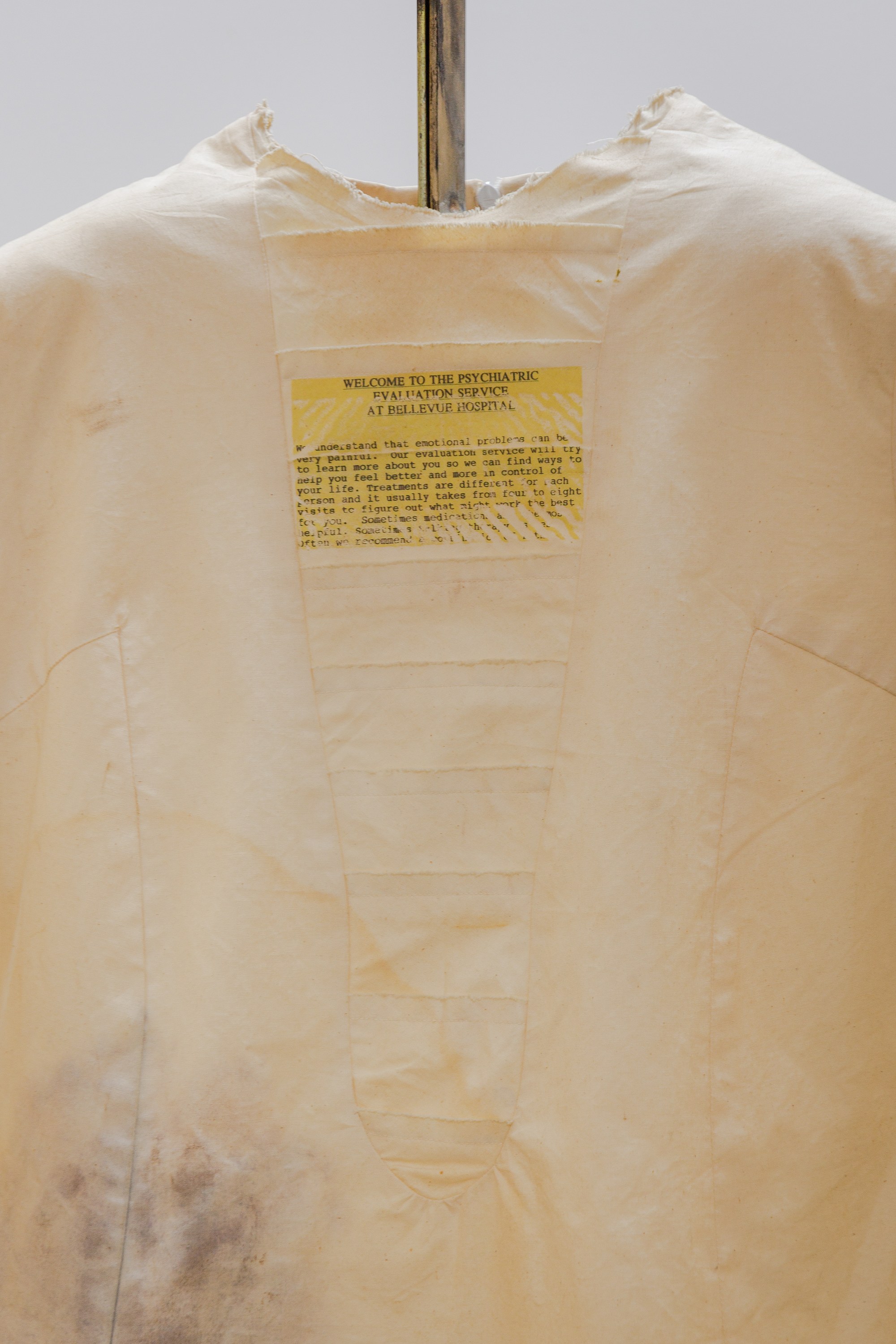 Patricia Ayres, Bellevue Hospital Dress, 2001- 2025, Detail, Muslin, text, paint, Ford Crown Victoria Police Interceptor restraint bracket, 40 x 30 x 8 in