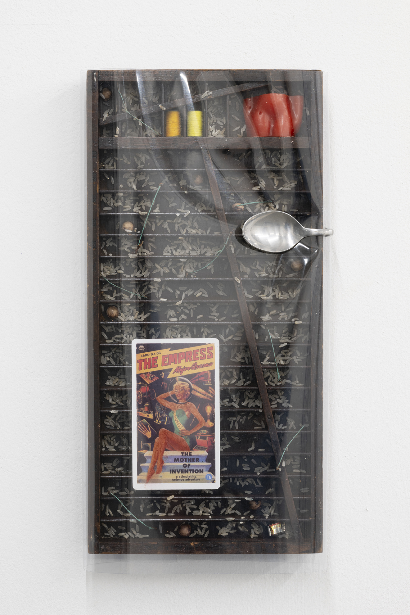 Marcelline Mandeng Nken, The Mother Of Invention, 2025, Pvc plastic, stained wood, empress tarot card, beeswax, rice, cherry seeds and stems, thread, silver spoon, 40 x 19 x 3 cm, courtesy of Cordova. Photography by Roberto Ruiz.