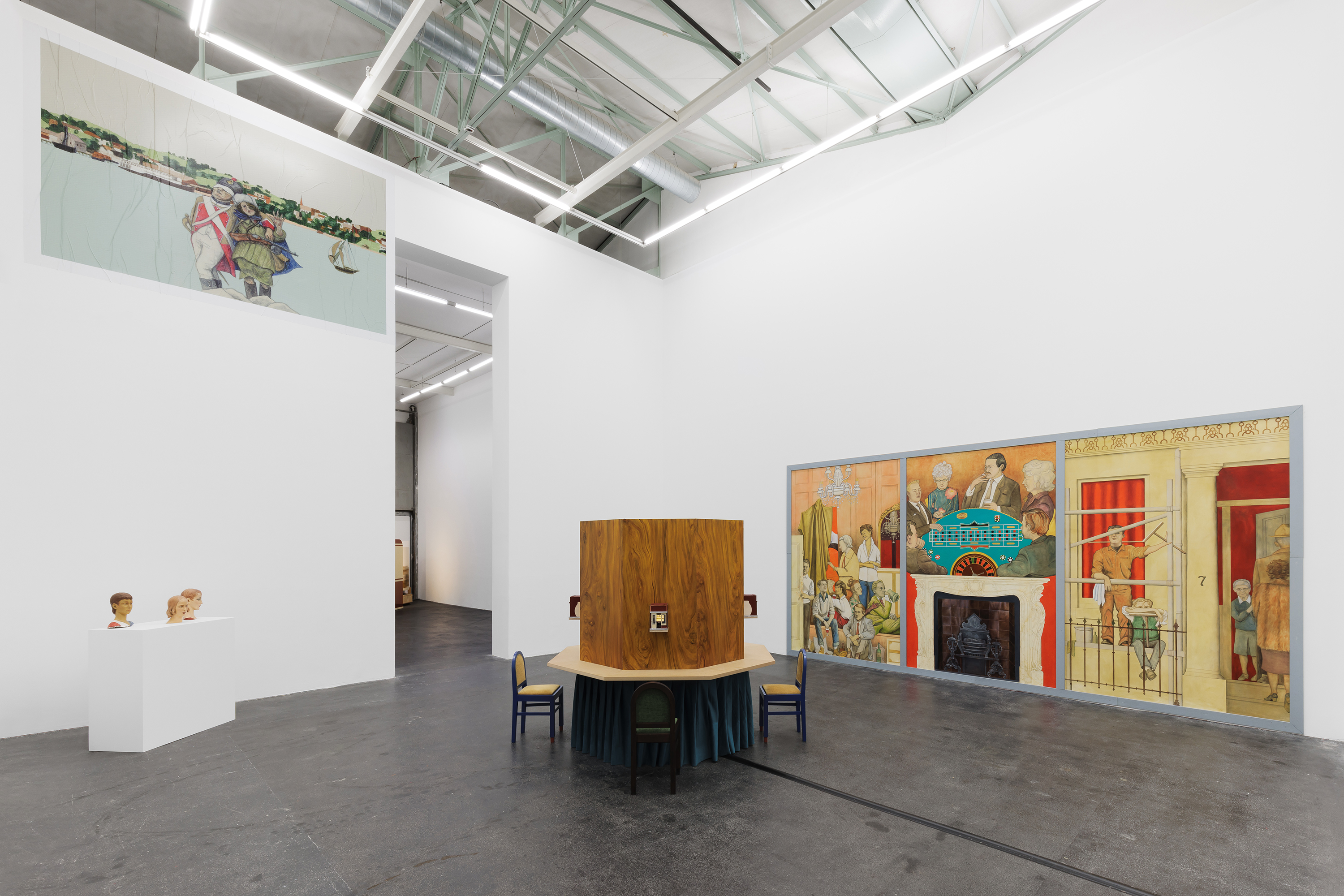 Installation view, Lucy McKenzie: Plastic Newspaper (2026), Crac Occitanie, Sète. At centre: Miniature Moving Panorama (Hudson Valley), 2024. Wood structure, model trains, textile, motor, acrylic and oil on canvas, 4 chairs, 210 × 212 × 212 cm. Courtesy of the artist and Galerie Buchholz, Cologne. Left, on plinth: Anonymous Youth, Donatello John the Baptist 1.1., Donatello John the Baptist 1.2., Donatello John the Baptist 2, 2019. Oil on fibreglass-reinforced plastic (except Donatello John the Baptist 1.2., oil on plaster), 20 × 21 × 28 cm / 30 × 20 × 33 cm / 28 × 22 × 32 cm / 28 × 19 × 30 cm. Courtesy of the artist and Galerie Buchholz, Cologne. Left, on wall: Re-enactors, 2024. Digital print on paper, 250 × 380 cm. Edition: production Crac Occitanie. Courtesy of the artist, Galerie Buchholz, Berlin / Cologne / New York and Cabinet Gallery, London. Right: Mural for Cromwell Place (Francis Bacon’s Studio), 2024. Oil and acrylic on canvas, 300 × 600 cm. Courtesy of the artist, Galerie Buchholz, Berlin / Cologne / New York and Cabinet Gallery, London. Photo: Useful Art Services.