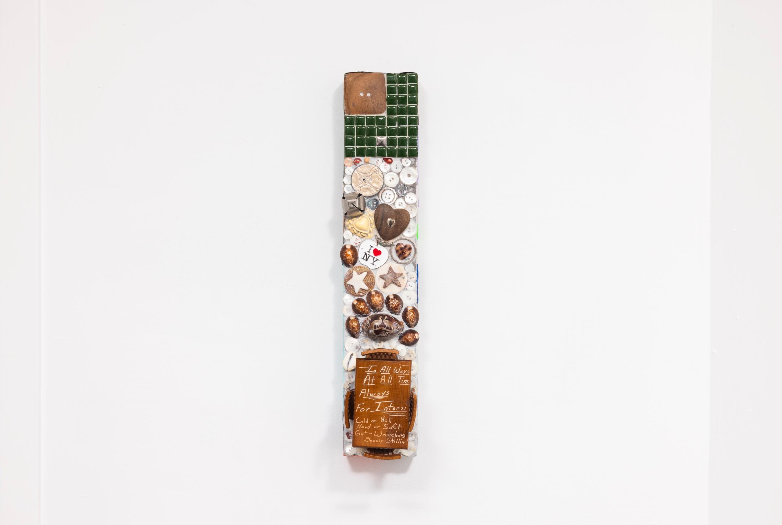 Faith Icecold, Distant Sound Effects, 2026 Pique assiette mosaic (mortar, grout, archival glue, wooden button, ceramic tiles, mother of pearl buttons, found buttons, silver bell, studded wooden embellishment, found material, I ♡ NY keychain, cowrie shells, laser-engraved miniature table set on wood), pigmented encaustic, encaustic on inkjet prints on paper and laser-jet on paper 18 × 6 × 4 in. (45.7 × 15.2 × 10.2 cm). Courtesy of the artist and Romance.