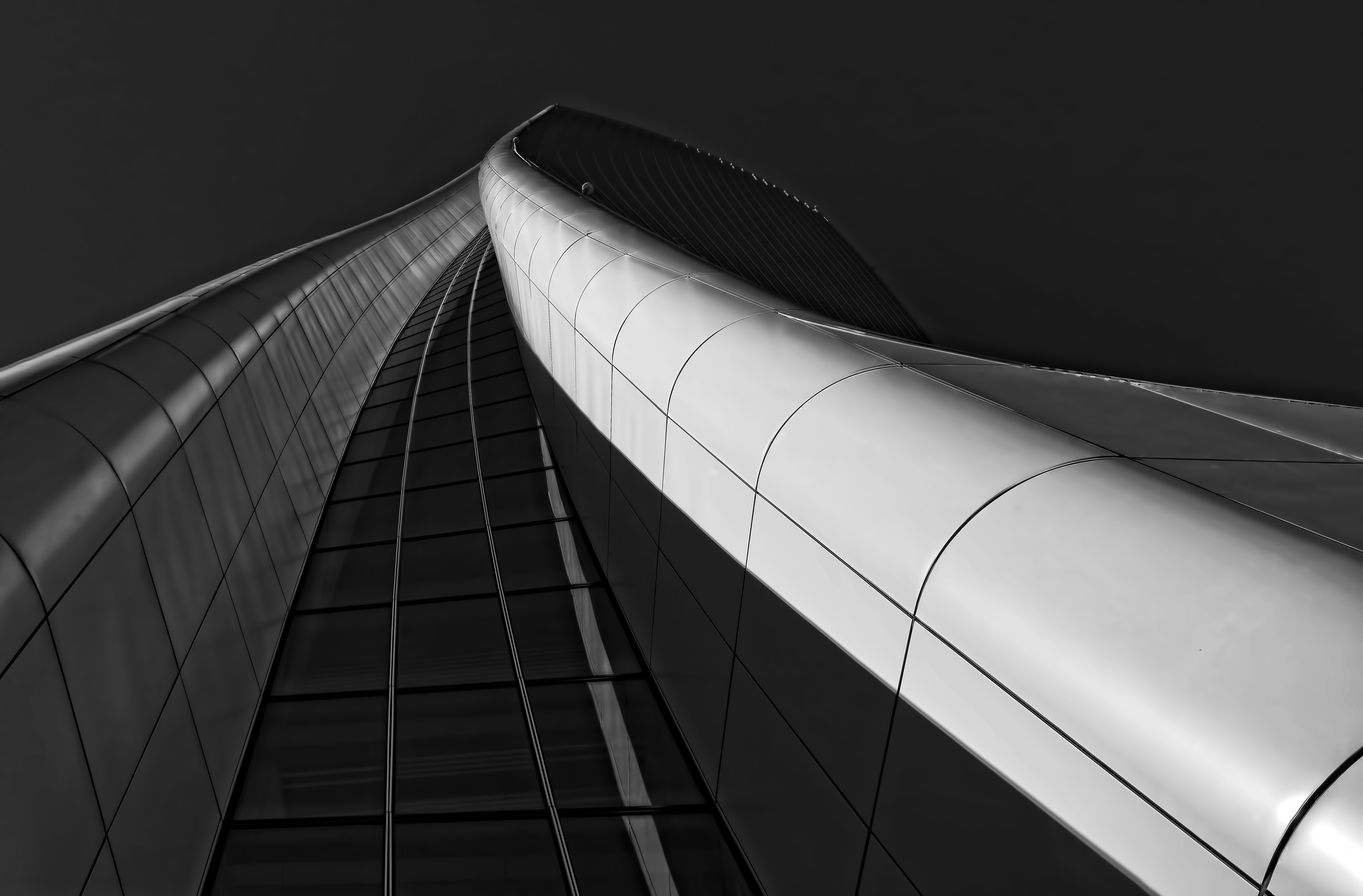 Black and white image of tall, twisted steel building with a vertical line of windows down the center