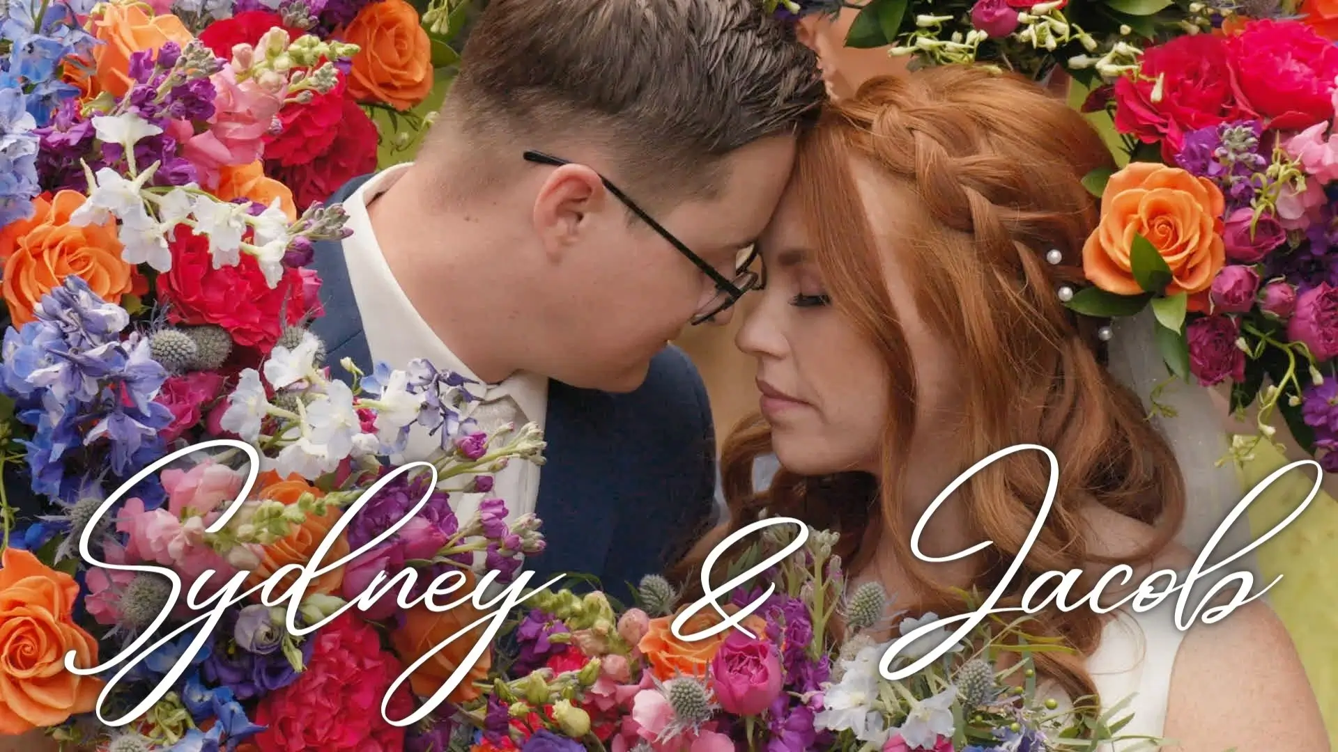 Sydney and Jacob, the bride and groom, share an intimate moment surrounded by vibrant Michigan flowers in this still from their wedding video. Their names are elegantly displayed across the bottom of the thumbnail for their wedding video.