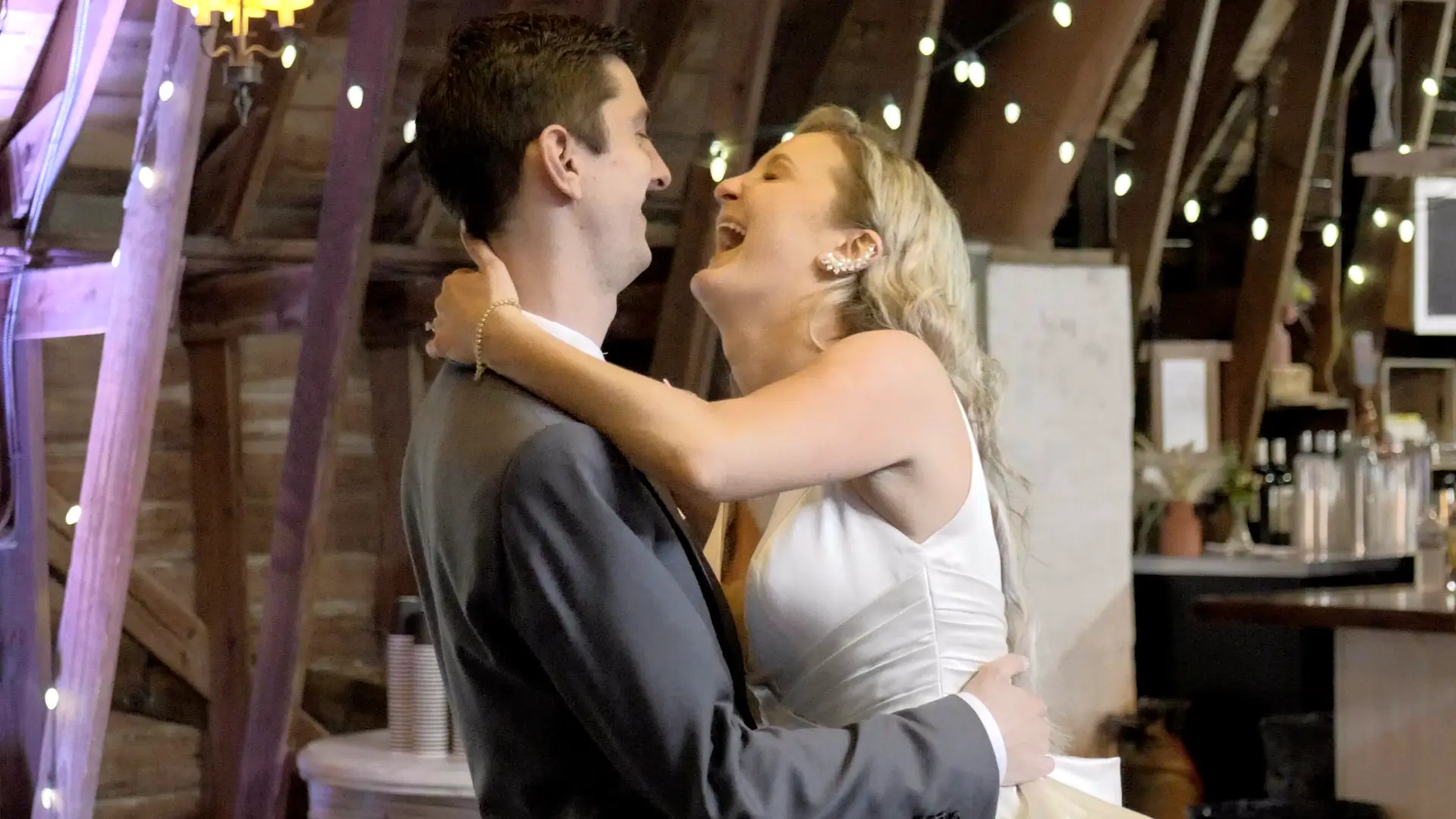 Jessica and Patrick share a joyous moment in this still from their wedding video at the Blue Dress Barn. Jessica laughs while embracing Patrick, capturing the fun, laid-back atmosphere of their special day.