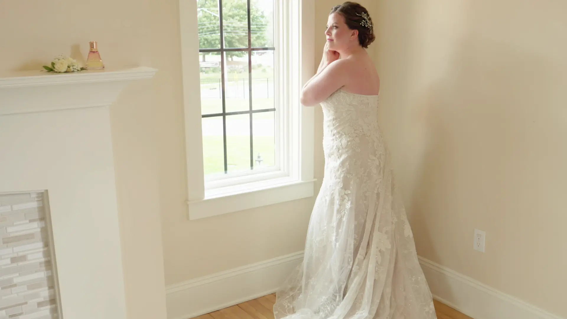 Bride Leah gazes out a window in her wedding dress during a thoughtful moment captured by her wedding videography at Venue3Two in Grand Rapids, Michigan.
