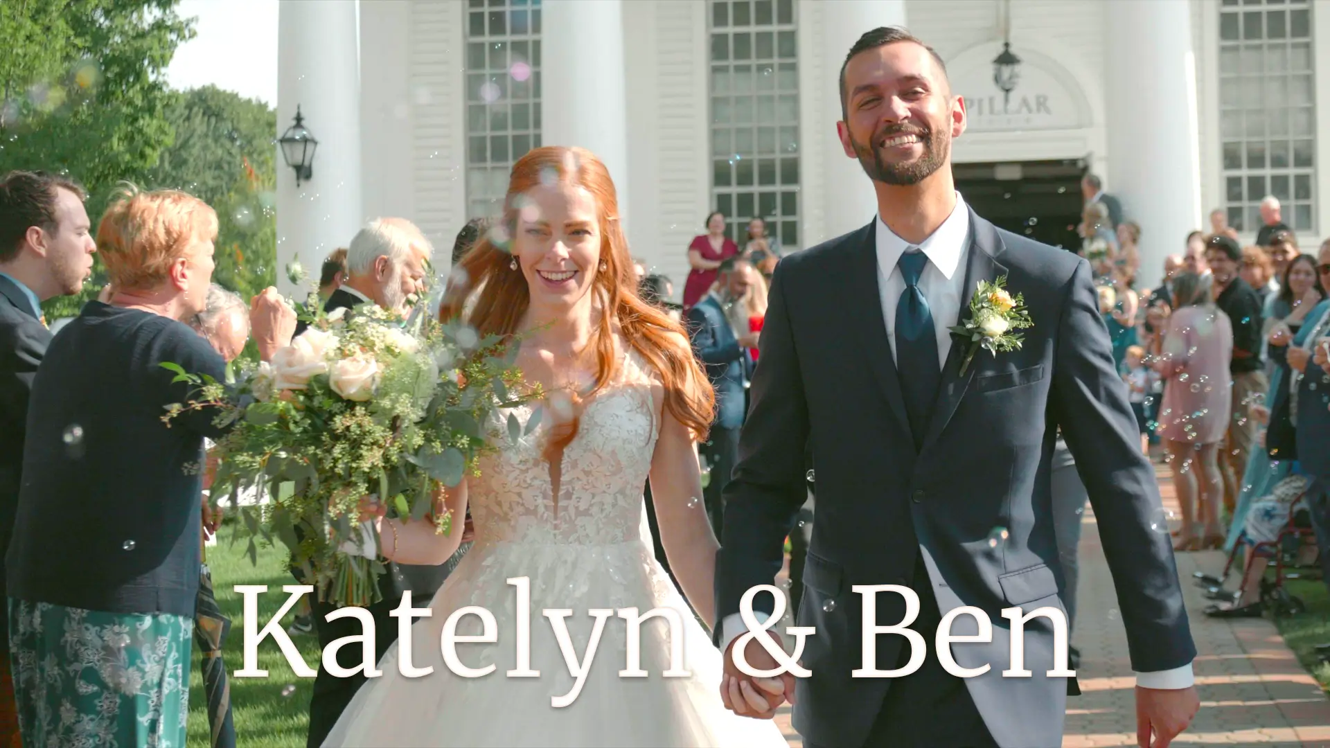 Katelyn and Ben, joyful after their wedding ceremony, holding hands and smiling as they walk through a crowd of well-wishers blowing bubbles. The couple is framed by lush greenery and an elegant church building in the background.
