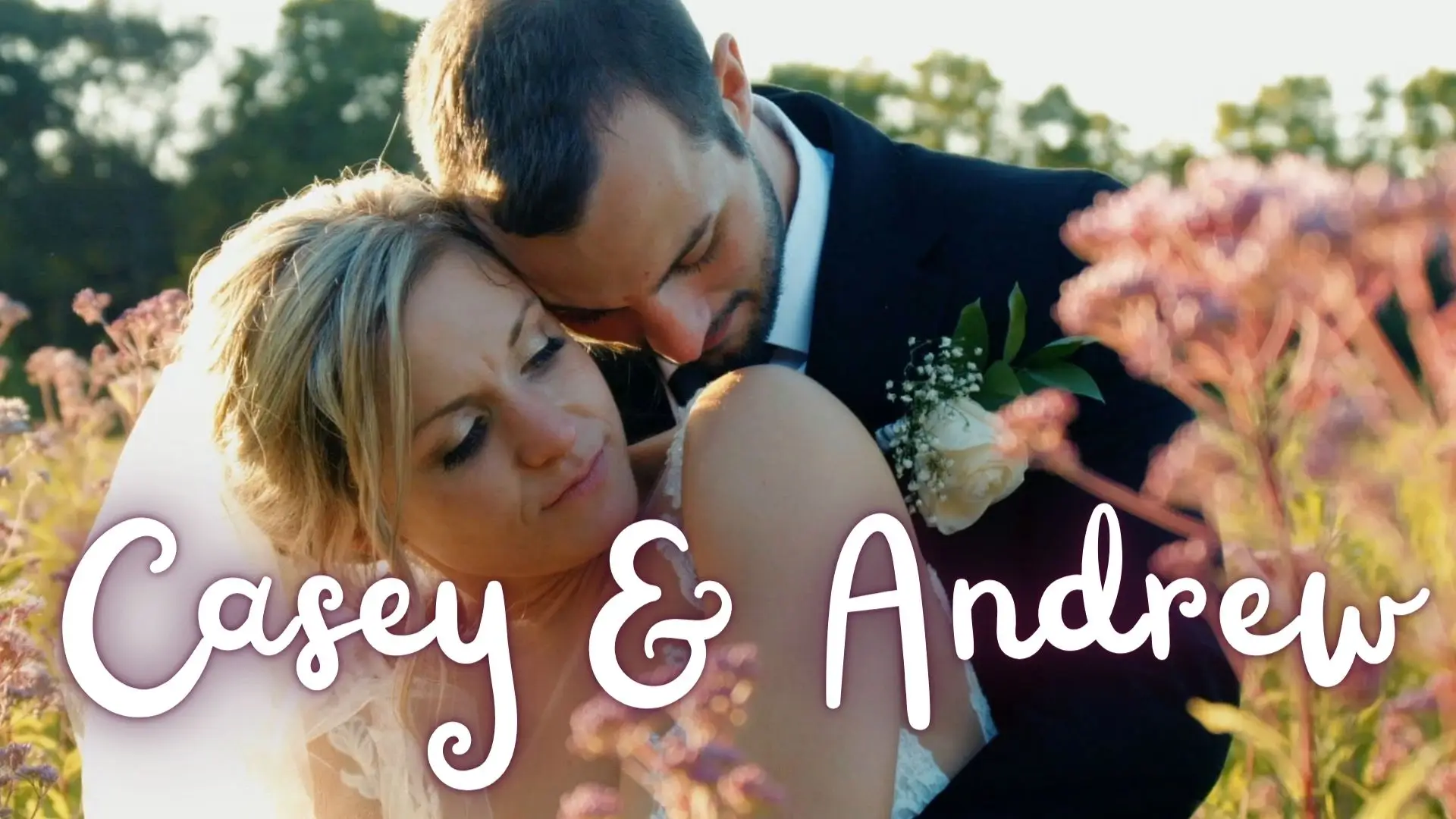 Casey and Andrew embrace amid vibrant Michigan wildflowers, with their names in cursive at the bottom of the image. The groom rests his head on the bride's shoulder, creating an intimate and serene moment.