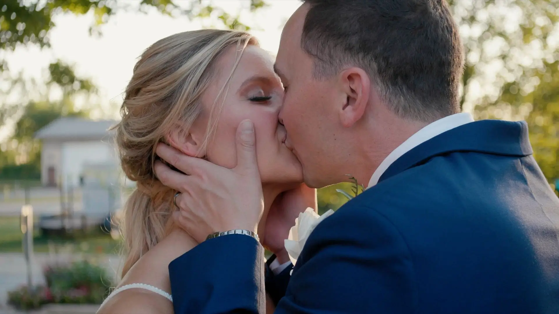 In this romantic snapshot from their wedding video, Bethany and Nick share a kiss under the vibrant Michigan greenery, capturing their love on their special day in Grand Rapids.