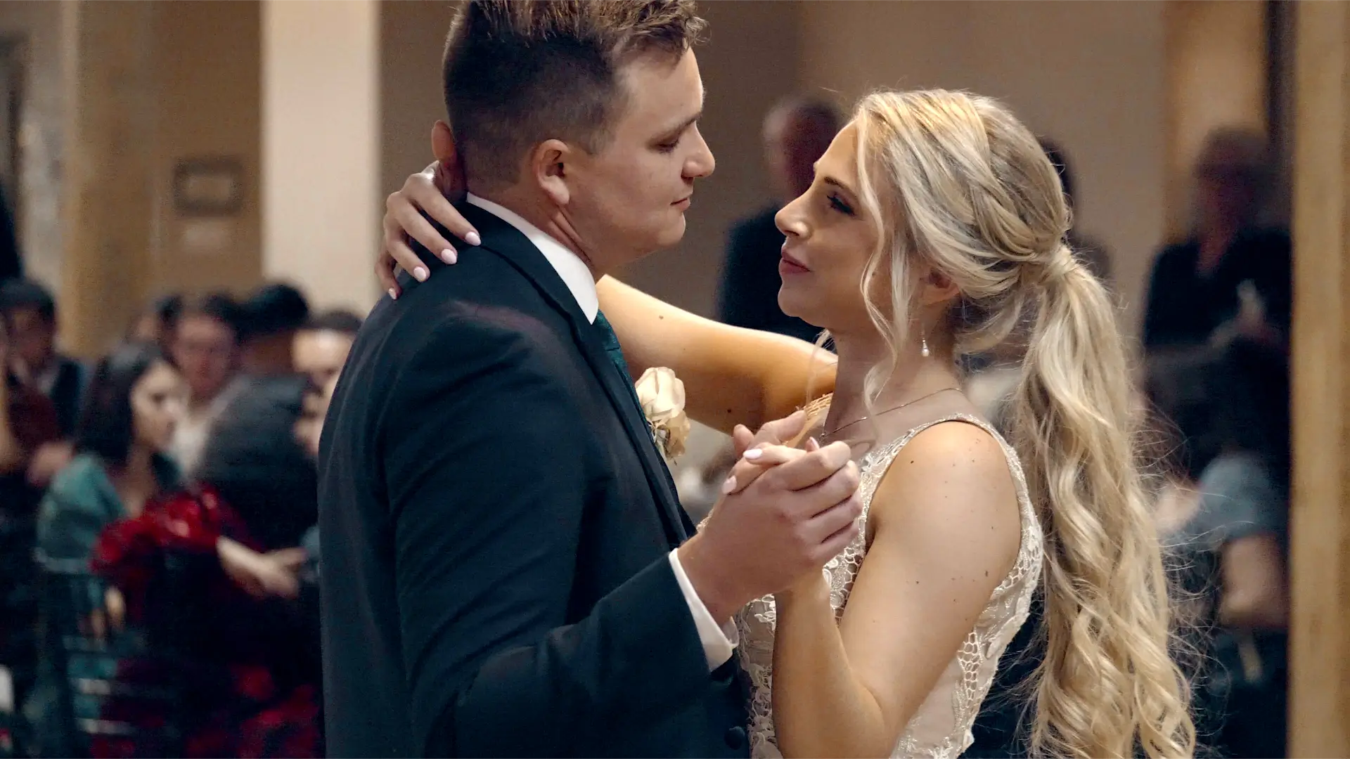 In this still from their wedding video in Grand Rapids, Mason and Dana share their first dance as a married couple, gazing lovingly into each other's eyes while guests watch in the background.