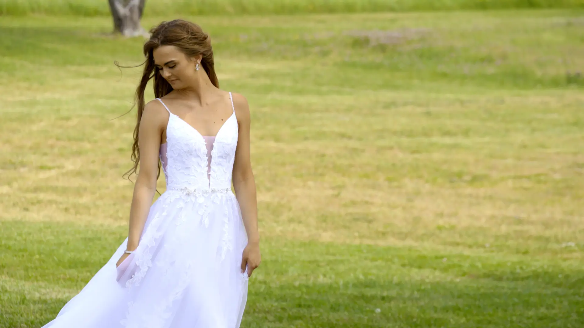 Bride Mikayla in a white wedding dress standing on lush greenery at Apple Valley Event Center in Sparta, Michigan.