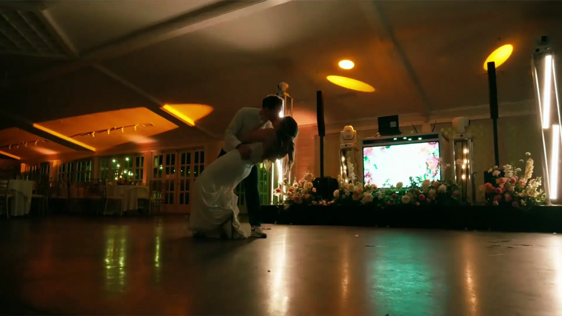A couple shares a romantic last dance in a warmly lit room at Castle Farms in Charlevoix, Michigan. The dance floor is empty except for the two of them, and the DJ's lights reflect around the room as the two share a kiss.