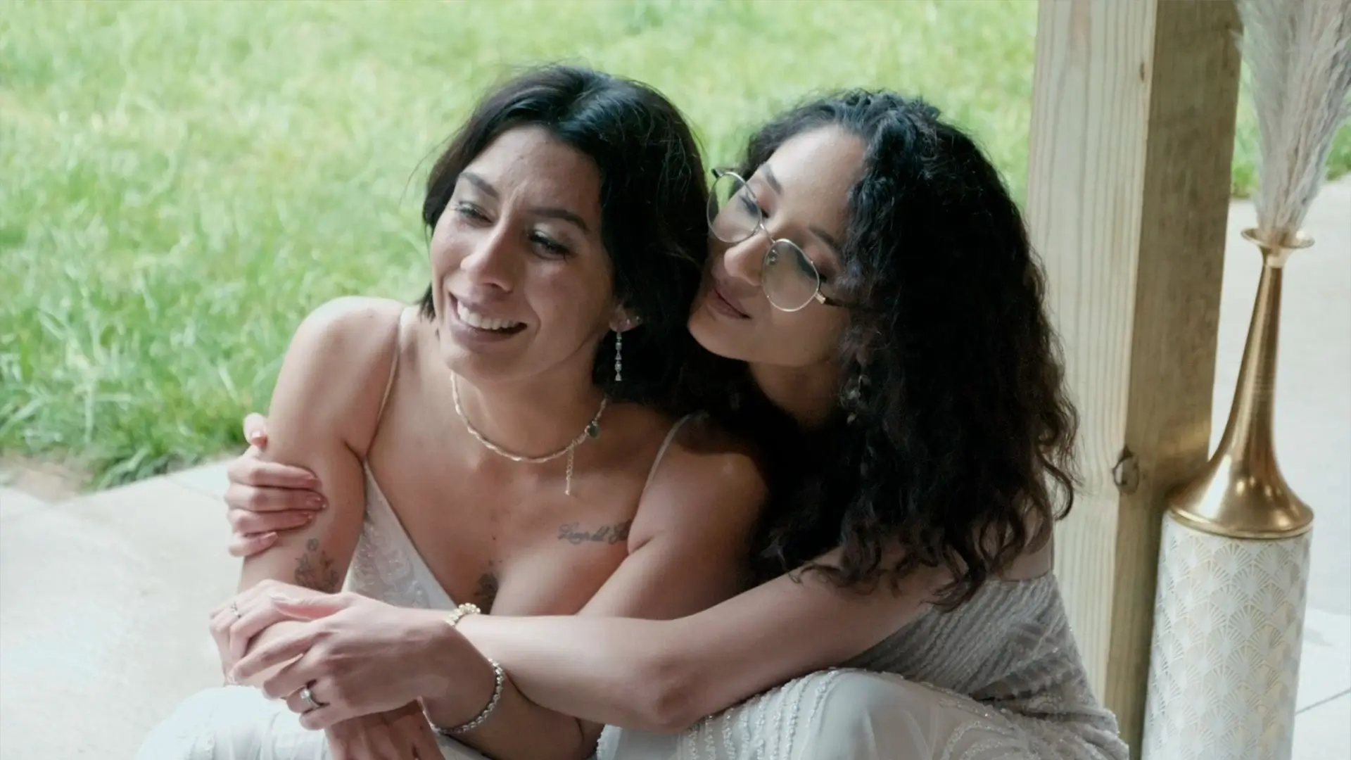 Irene and Claudia share an intimate embrace in their wedding highlight video at a private Airbnb in Newaygo. The brides are smiling and leaning against each other, reflecting the love and joy of their special day.