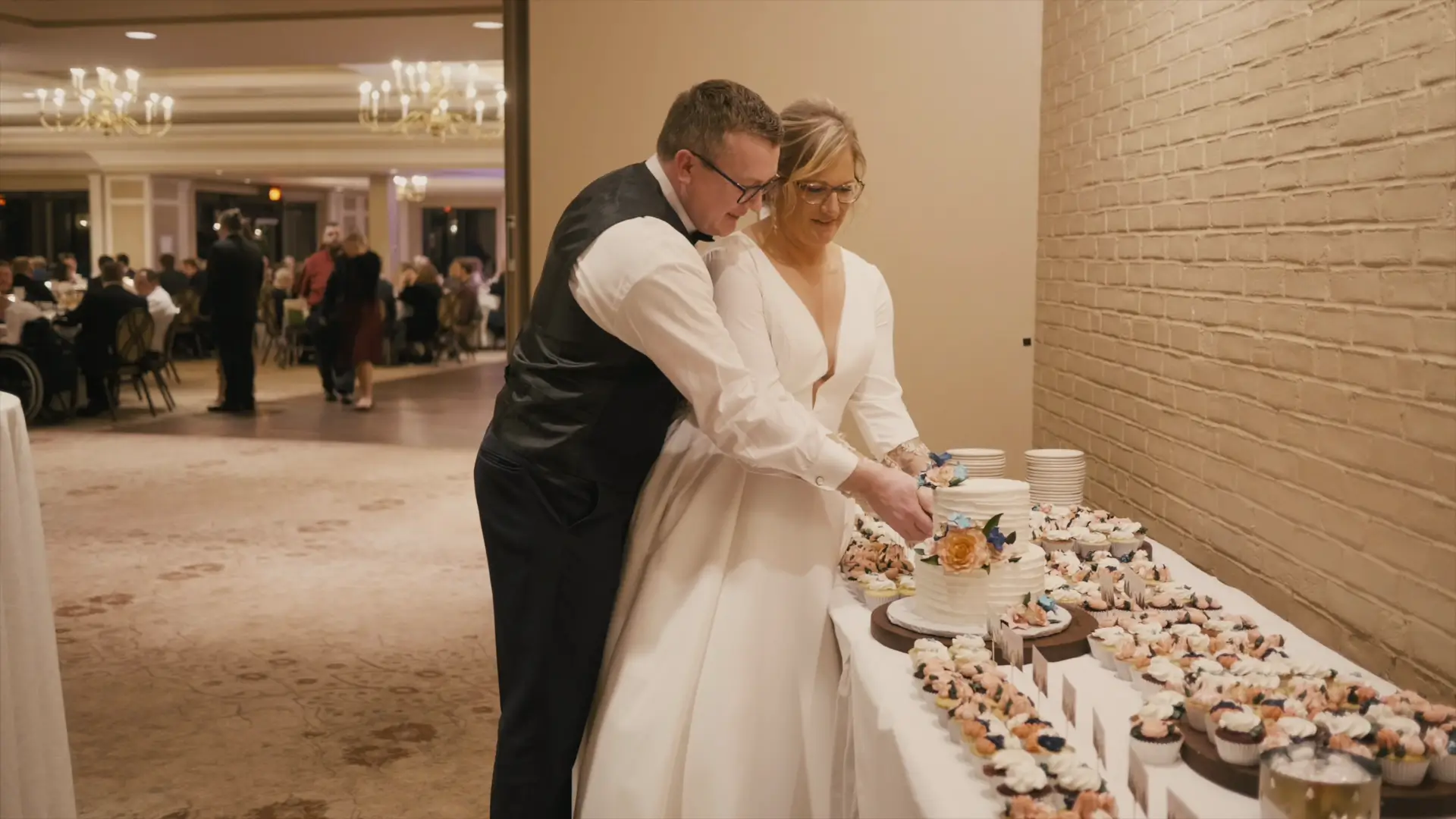 In this snapshot from their wedding highlight video, Billie and Stephen cut their wedding cake together at the Country Club of Jackson, surrounded by an elegant display of cupcakes.