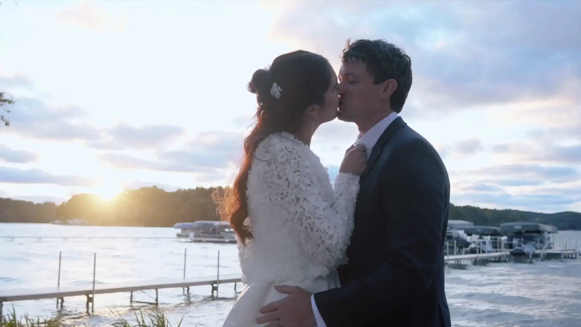 Bride and groom share a romantic kiss at sunset by the beautiful Michigan waterfront during golden hour.