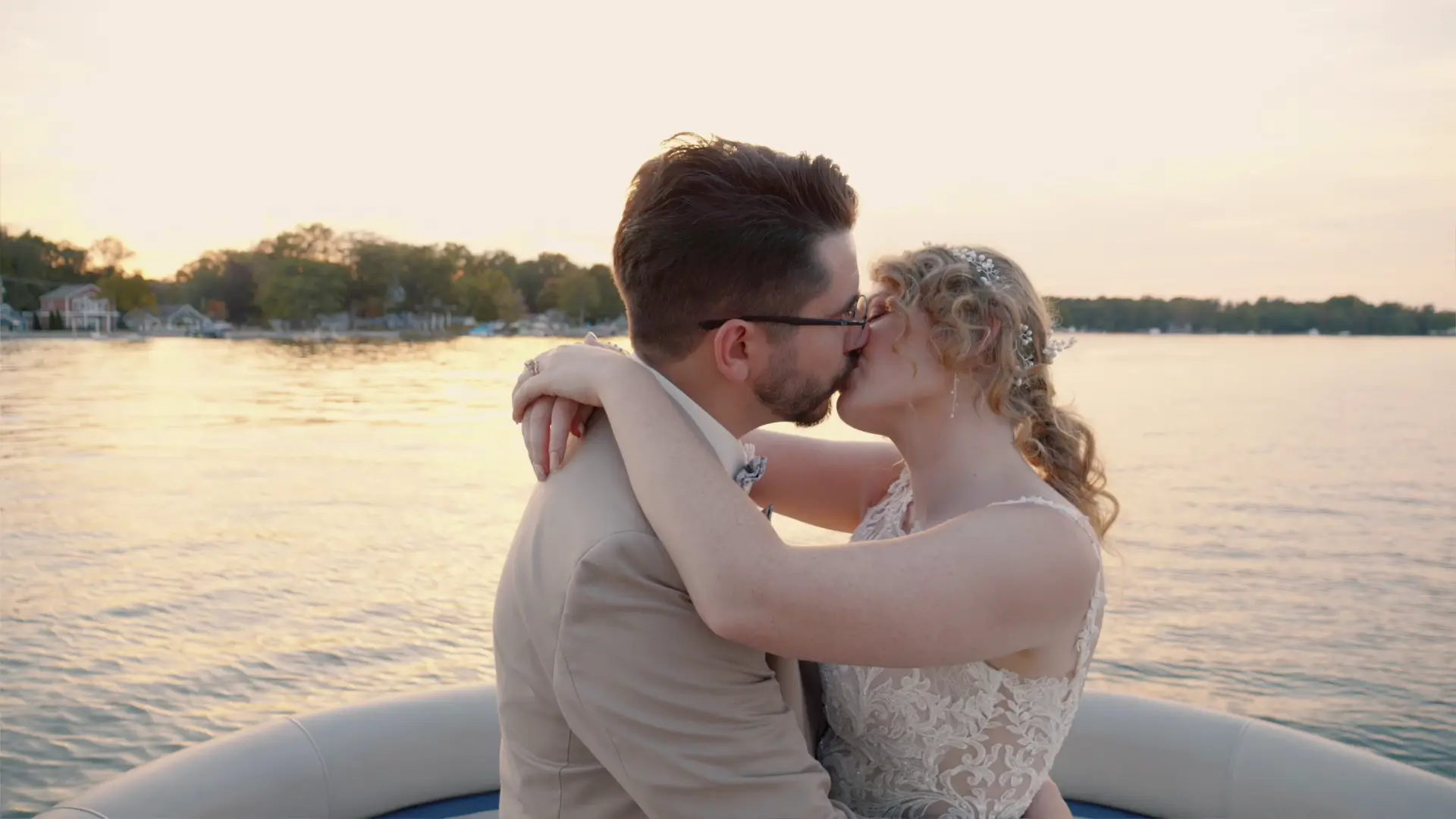 A couple kissing on a boat at sunset, captured by their wedding videographer at a lakeside location.