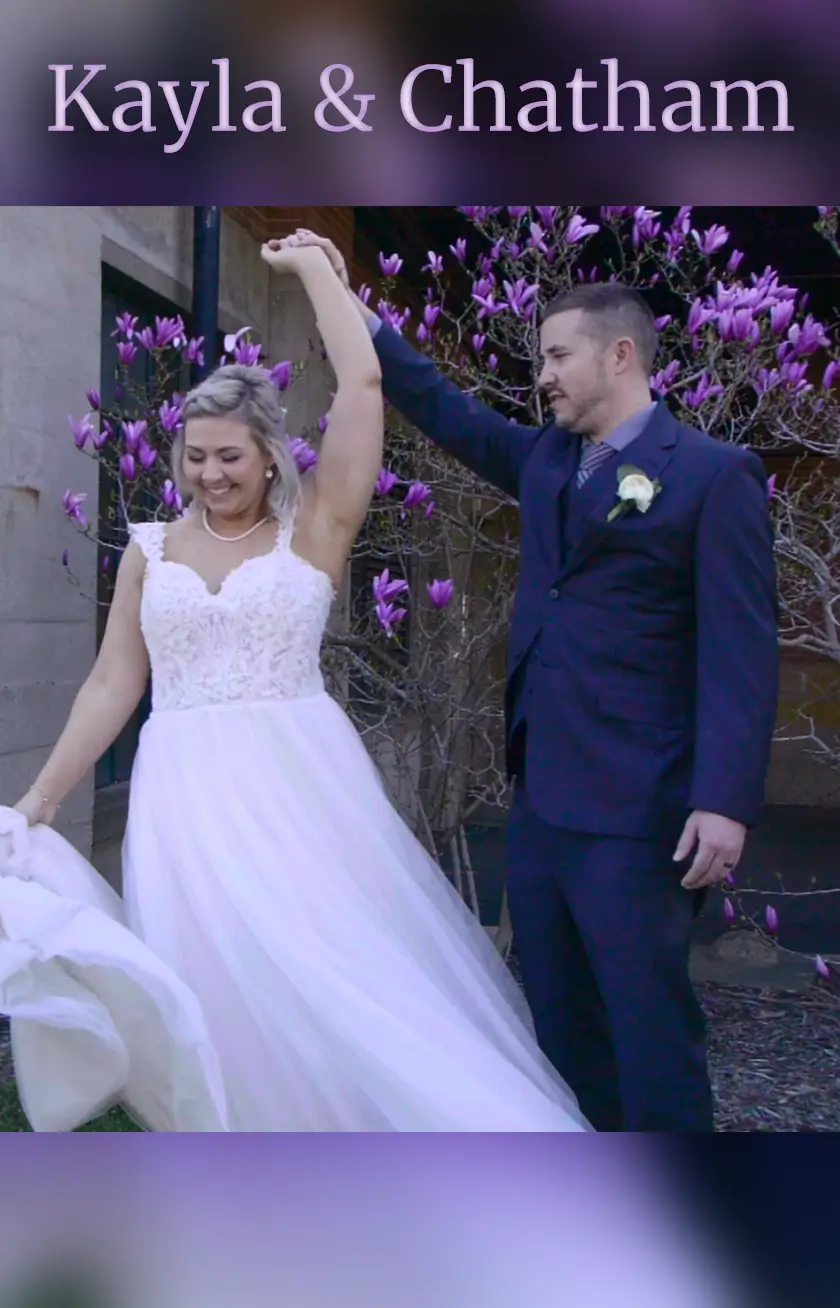 Bride Kayla and groom Chatham share a joyful moment for the wedding videographer against vibrant Michigan blossoms. Kayla spins in her gown as Chatham twirls her, capturing a lively scene from their Grand Rapids celebration.
