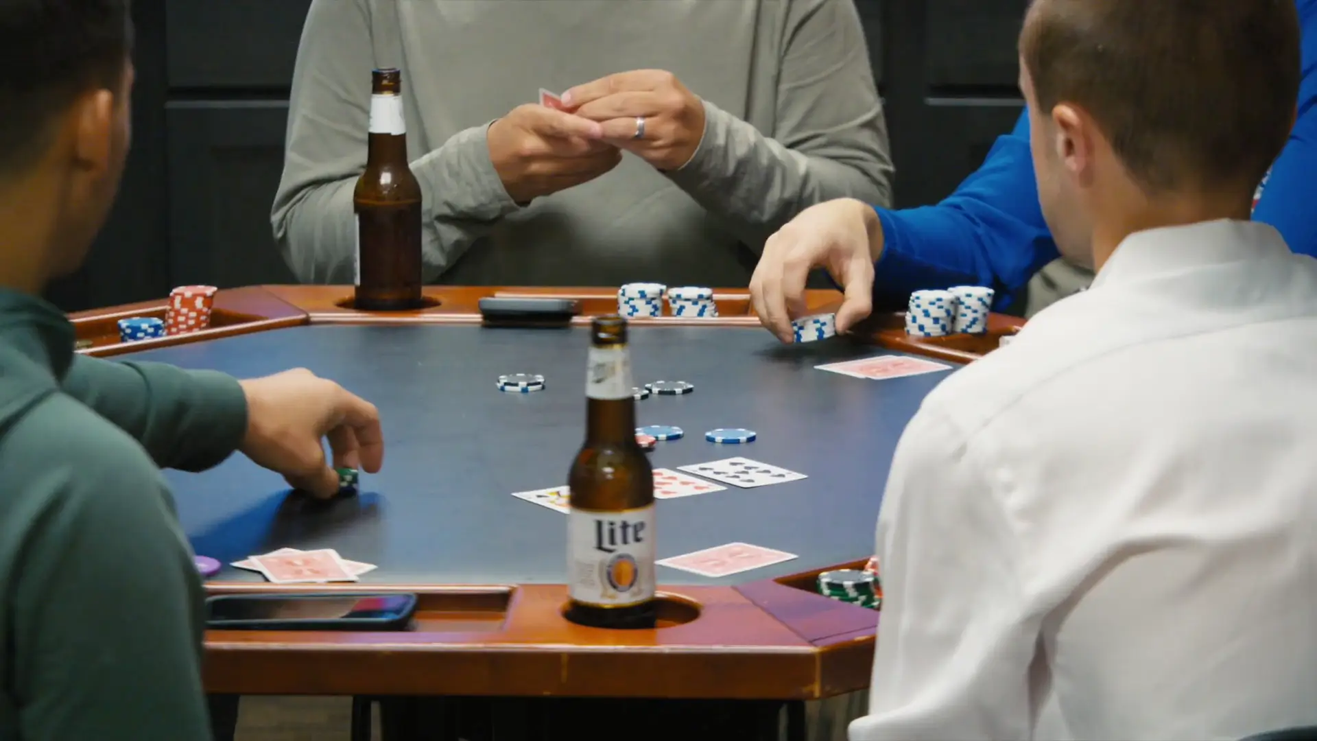 In this candid shot from Madison's wedding videography, friends play poker around a table with drinks and poker chips, capturing the relaxed atmosphere of the celebration.
