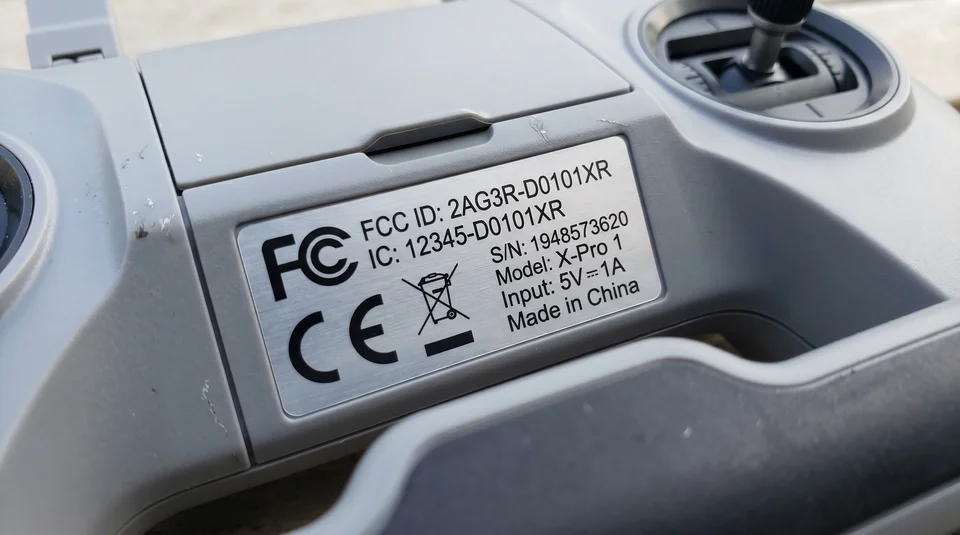 Close na etiqueta de homologação com FCC ID em controle remoto de drone. SLUG: close-etiqueta-homologacao-fcc-id-controle-drone