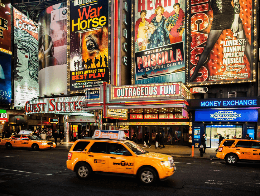 A picture of Broadway marquees and a taxi driving in front of a theater.