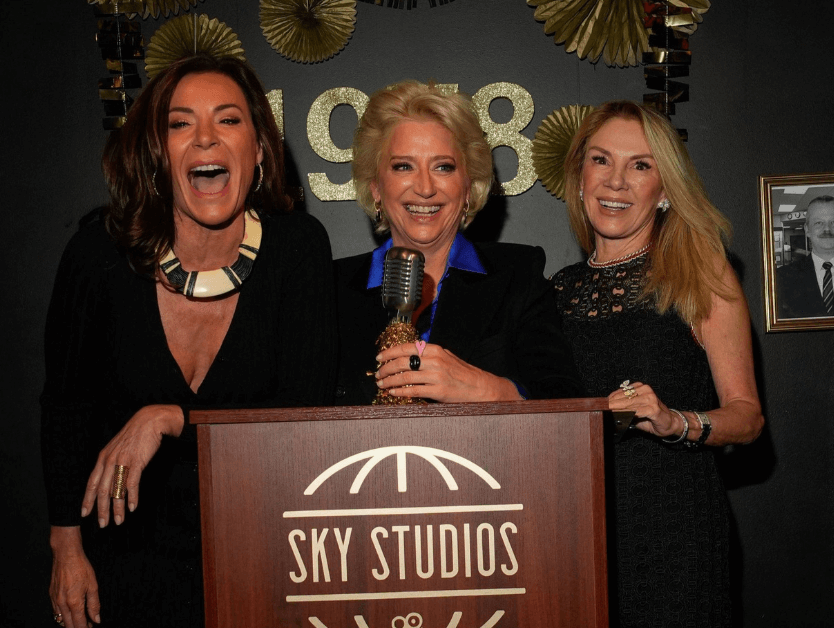 Three women standing behind a podium and smiling for a photo