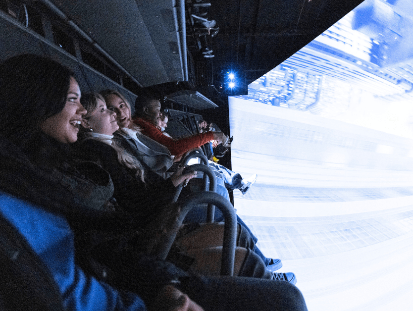 The inside of RiseNY at the ride portion of the attraction, people smiling and talking to eachother while riding