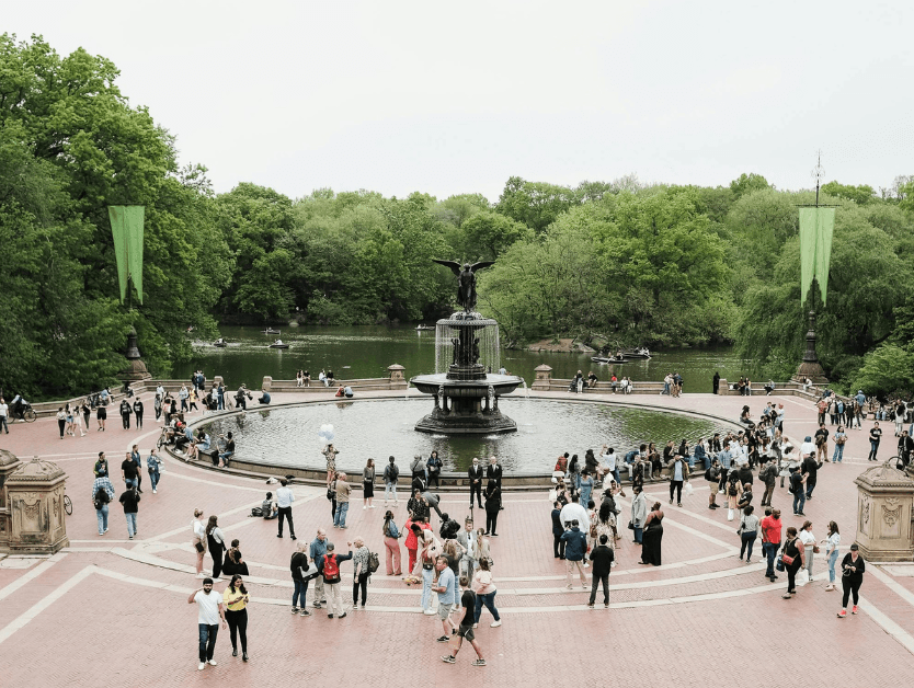A photo of the fountain in Central Park and people walking around enjoying the spring day