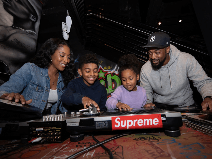 A family smiling for a photo as they look at a DJ deck at one of the many RiseNY exhibits