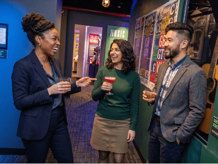 People smiling and enjoying drinks in one of the RiseNY exhibits during a corporate event