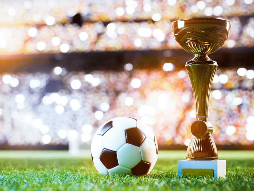 A soccer ball on a field next to a trophy