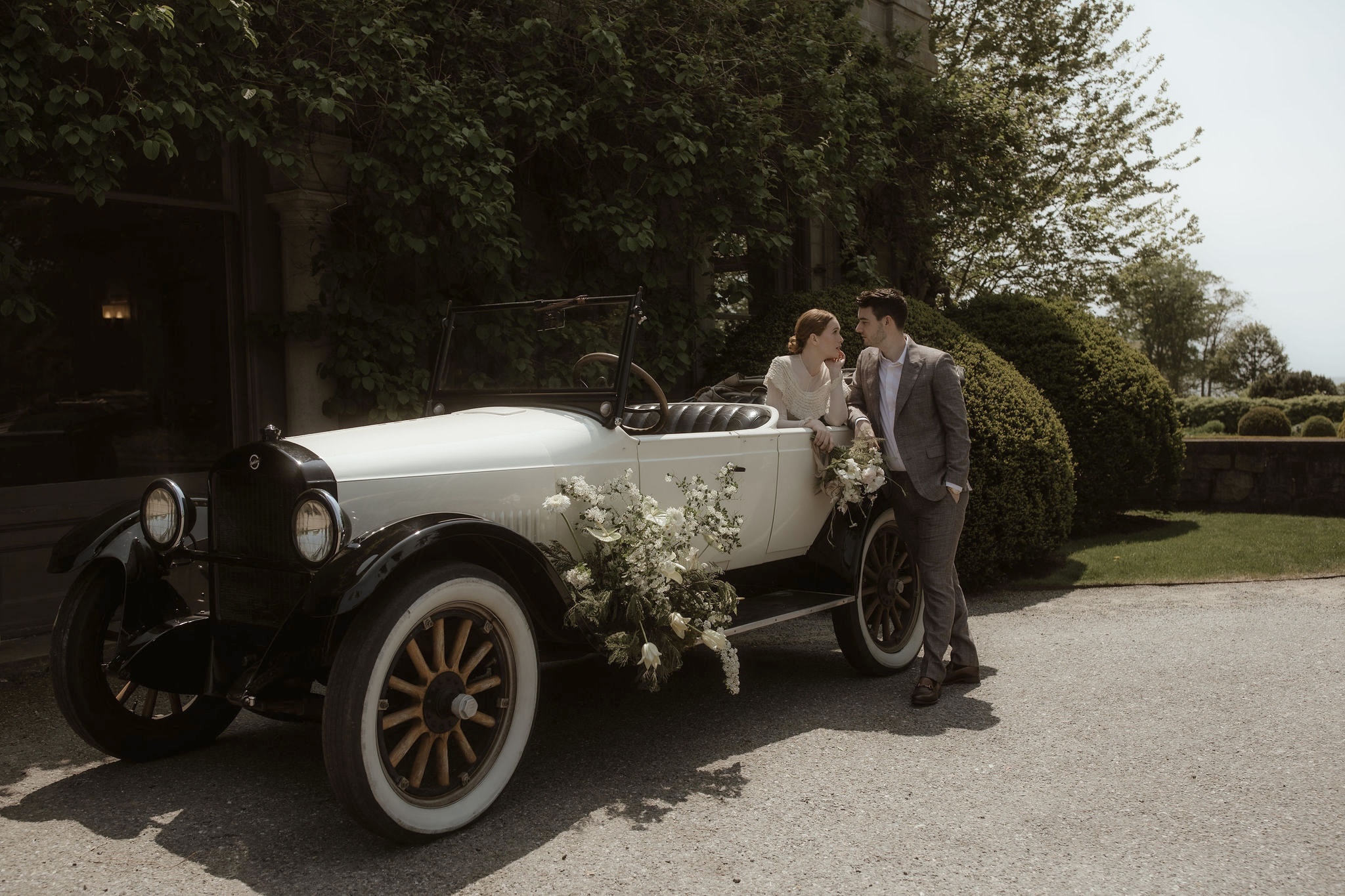 Rear angle of 1924 Studebaker Convertible with wood-spoke wheels driving scenic road in Newport RI – vintage rental by Newport Classic Car Co. for weddings, private tours, and photo shoots.