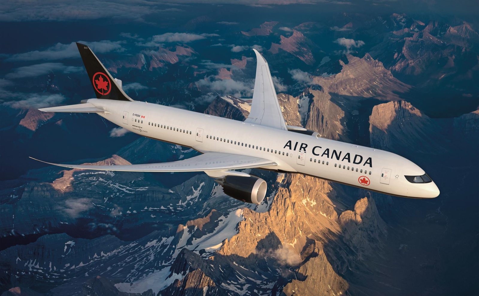 Air Canada aircraft in flight over snow-capped mountains