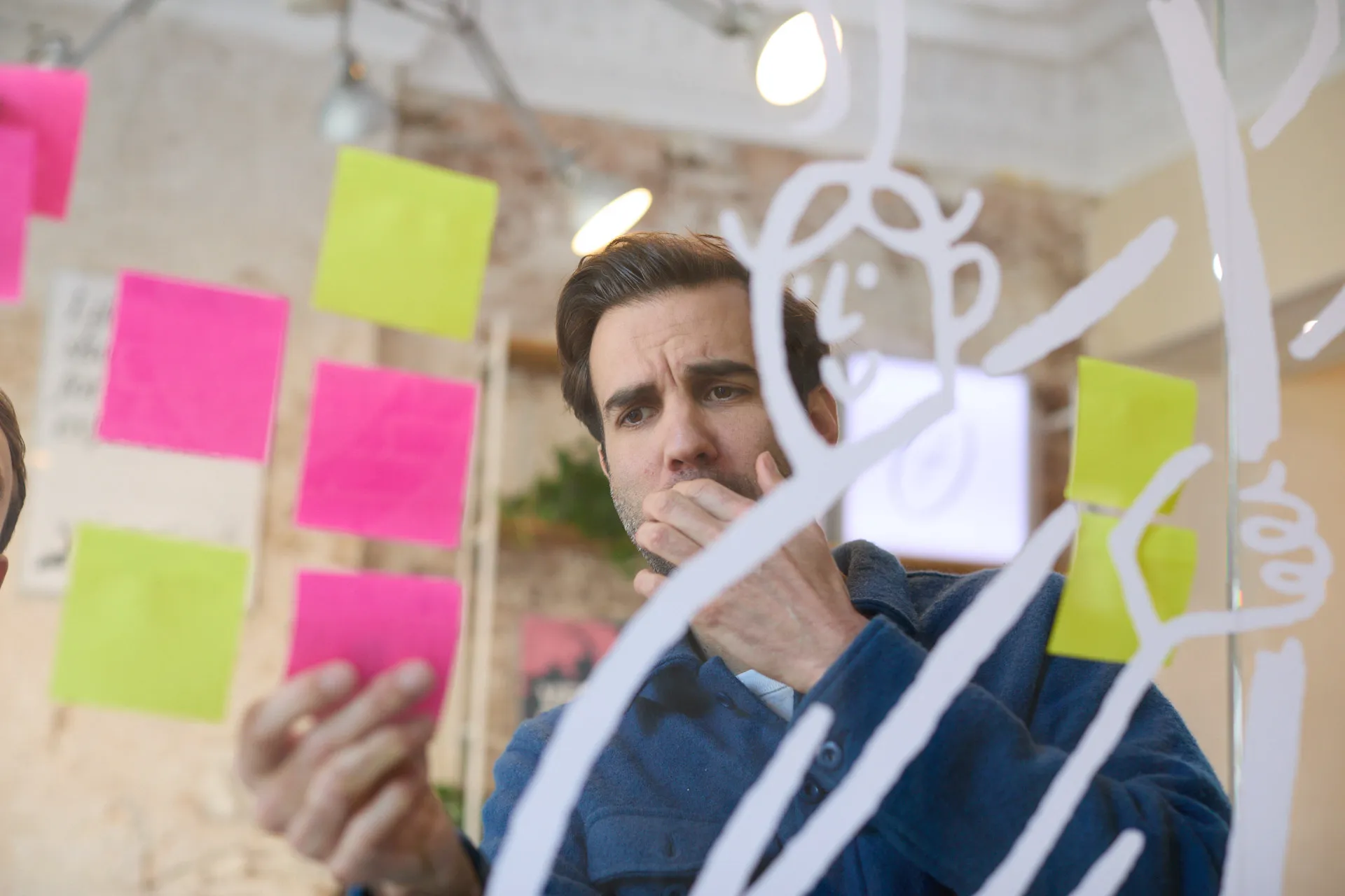 Designer van branding agency Evers + de Gier denkt na bij post-its en tekening op glazen wand in Rotterdam