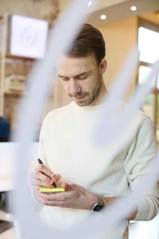Mans van Oosterhout schrijft een idee op een post-it nootje op het glas