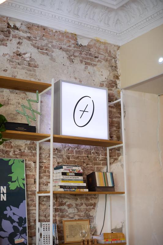 Verlichte E+dG lightbox op een boekenplank met designboeken voor een bakstenen muur