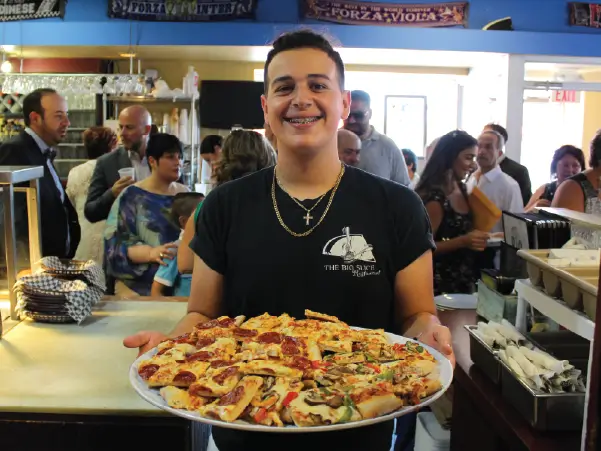 PICTURE OF YOUNG SALVATORE LUCIANNO, GRANDSON OF GIUSEPPE, HOLDING A TRAY OF PIZZA