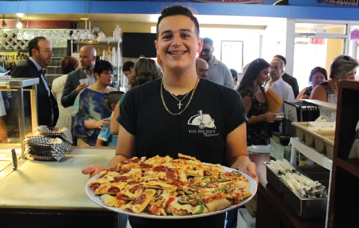 PICTURE OF YOUNG SALVATORE LUCIANNO, GRANDSON OF GIUSEPPE, HOLDING A TRAY OF PIZZA