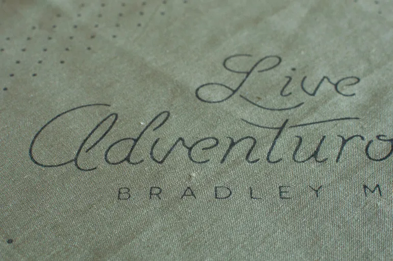 Close-up of the script lettering that reads Live Adventurously