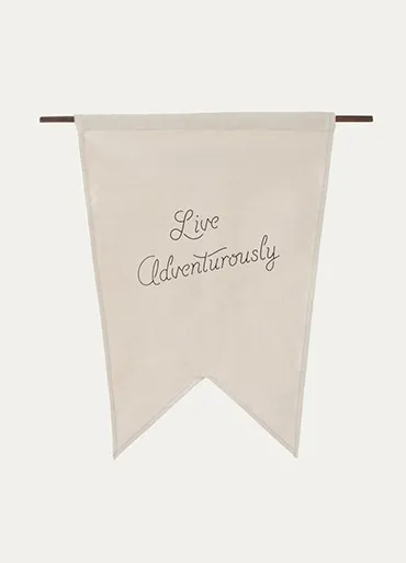 A natural cotton pennant flag, printed with the words Live Adventurously