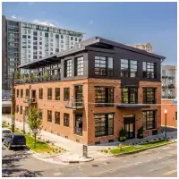 Modern three-story brick office building with large windows on a street corner in an urban area.