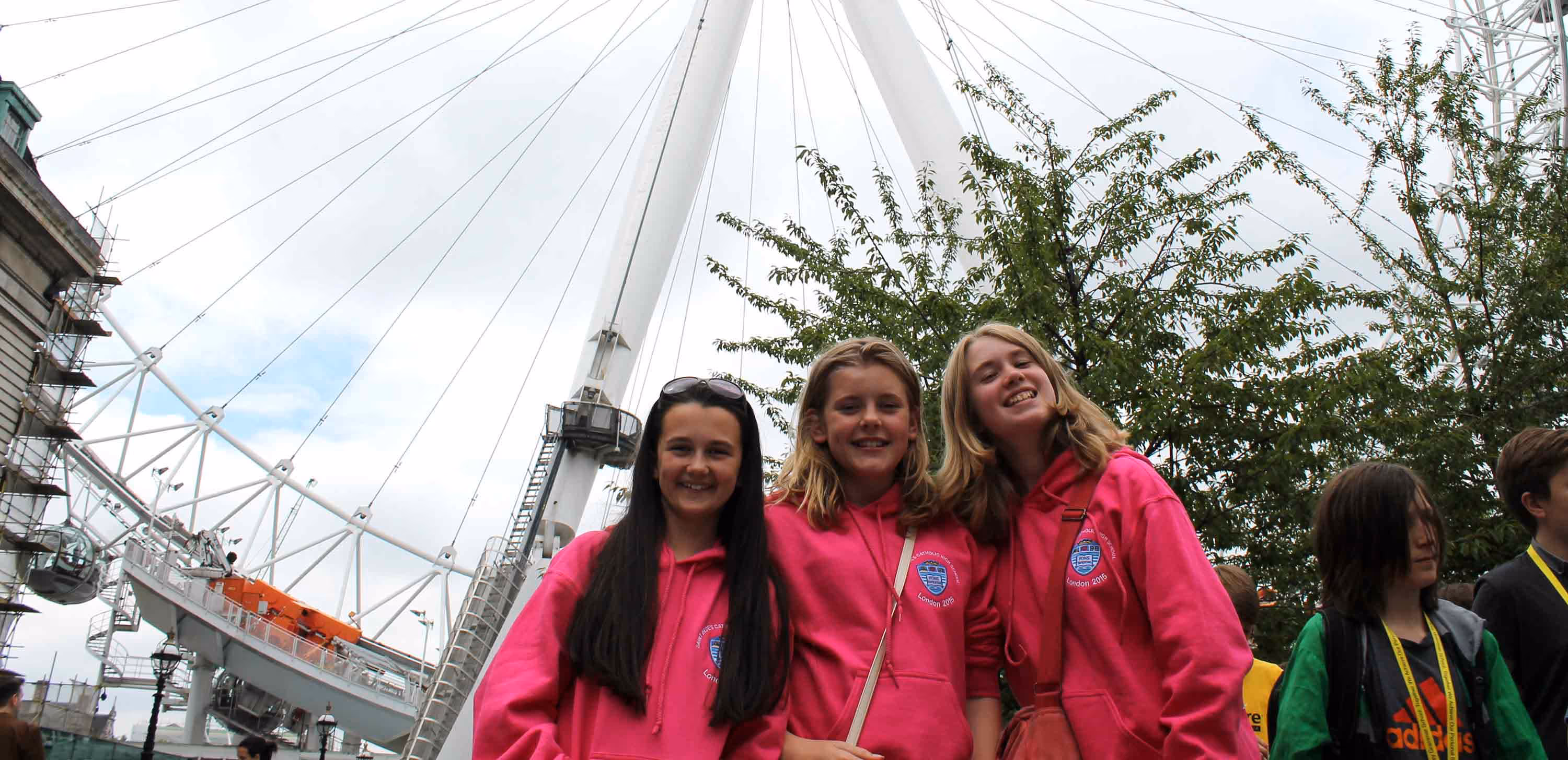 three girls wearing pink hoodies on a school trip