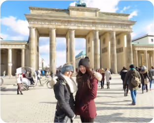 Two female students smiling for a picture in front of branderburger gate