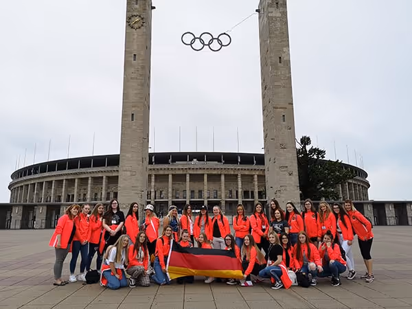 A big group of students wearing red, in front of the berlin olympic stadium