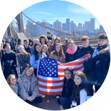A group of happy students on a school trip with american flag in their hand