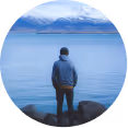 A man standing in front of a lake looking left