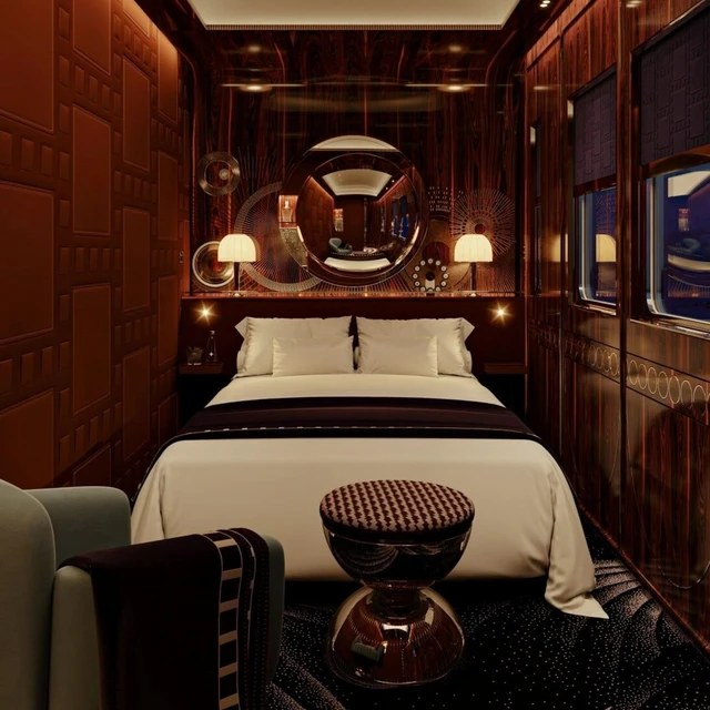 Wide-shot of a L'orient Express suite during the night, features a bed, as well as luxurious and intricate funishings.