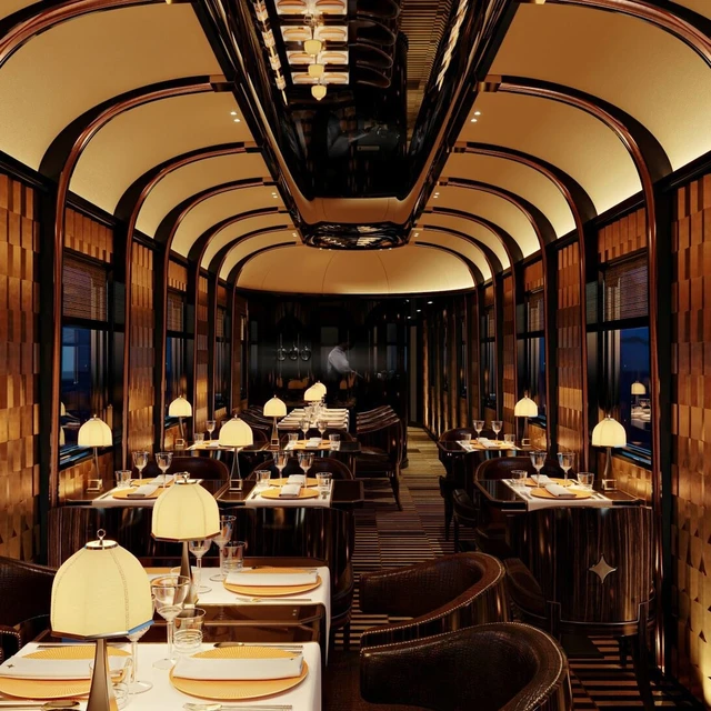 Wide shot of L'orient Express dining car in warm, intimate lighting.