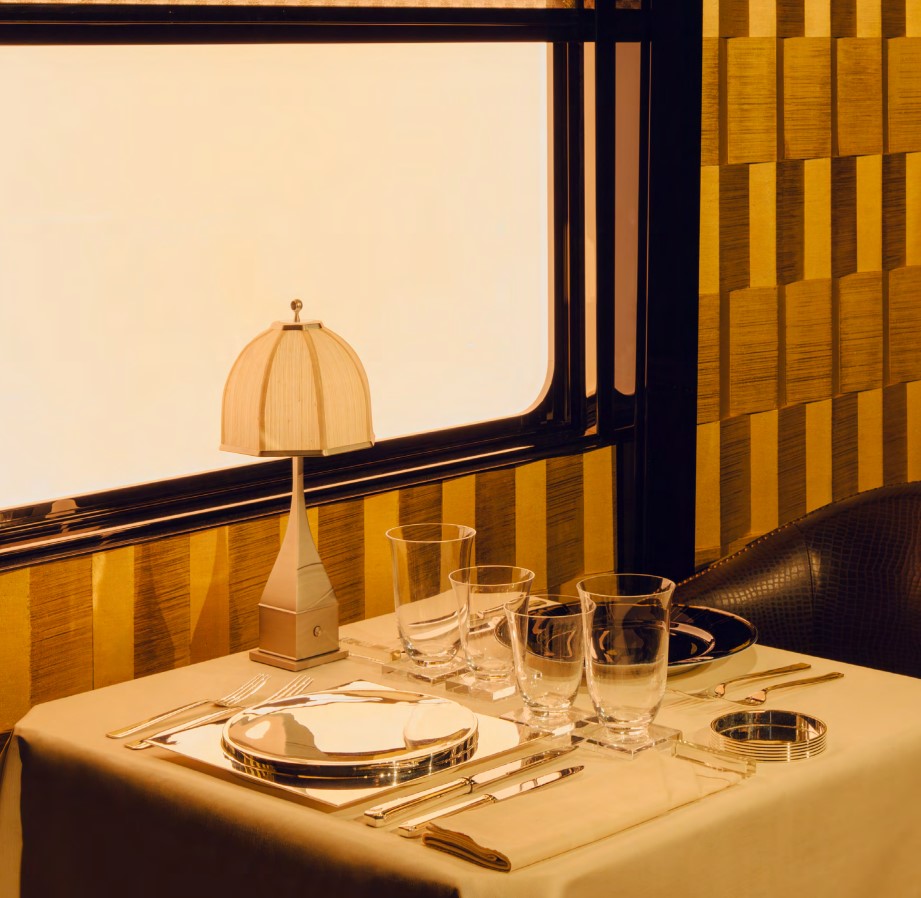 A set table with a lamp on L'Orient Express by the window. 