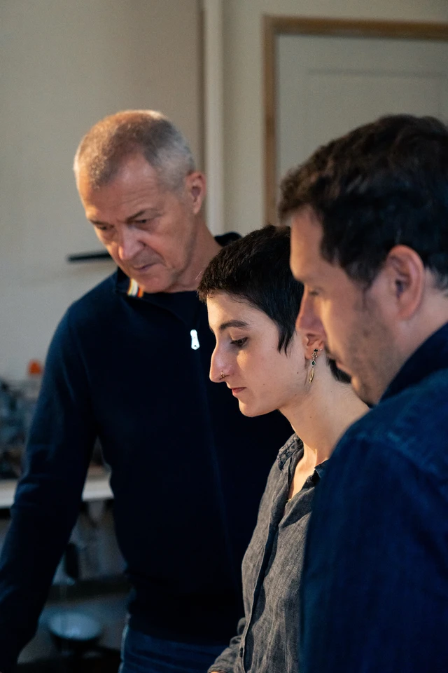 D'Angeac in conversation with two other people over, they are looking at something off-screen and are in discussion