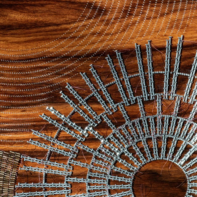 Close up of a work-in-progress embroidery on rosewood panelling